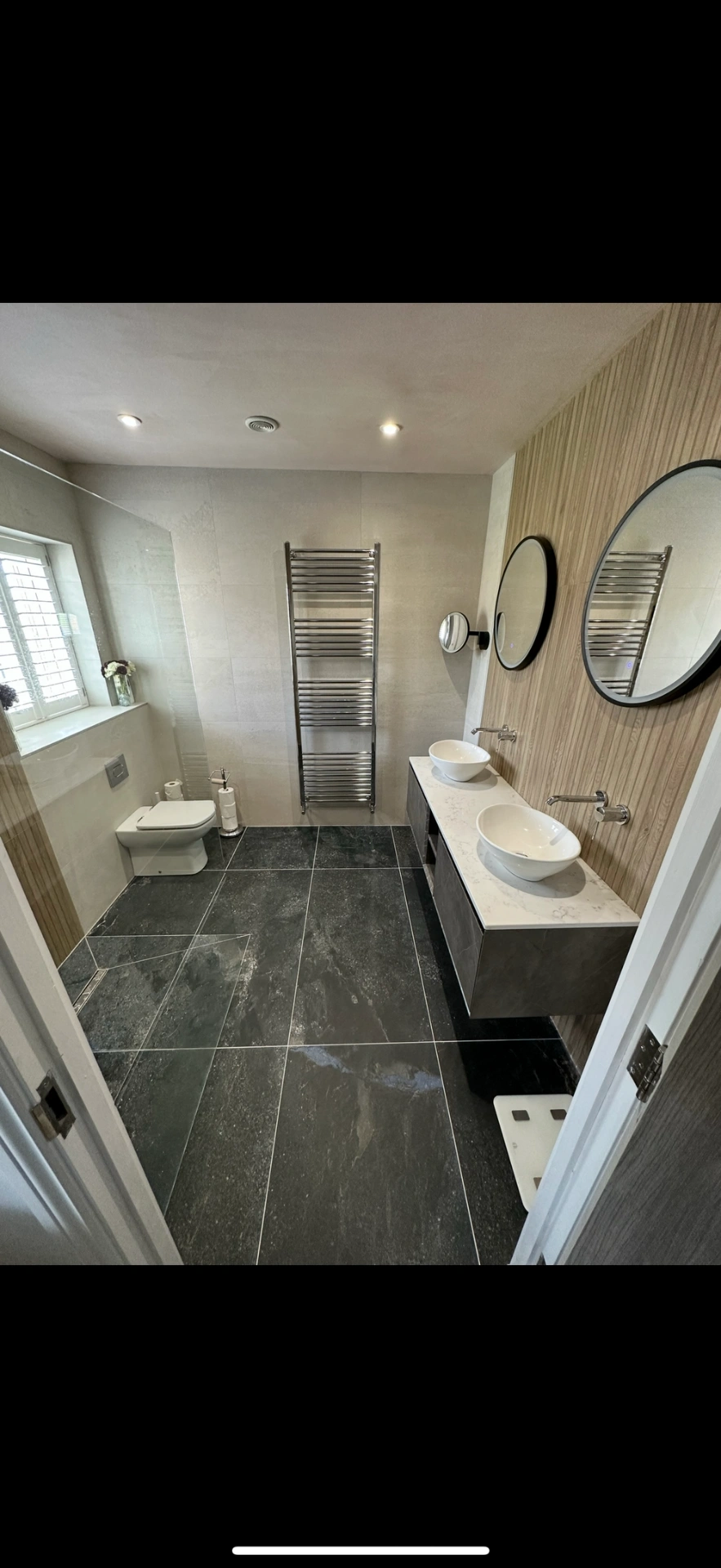 Spacious ensuite with slate floor, oak feature wall and twin vessel basins — Woking