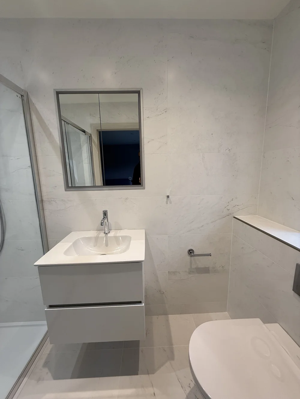 Compact marble ensuite with wall-hung vanity and back-to-wall WC — Woking bathroom fitters