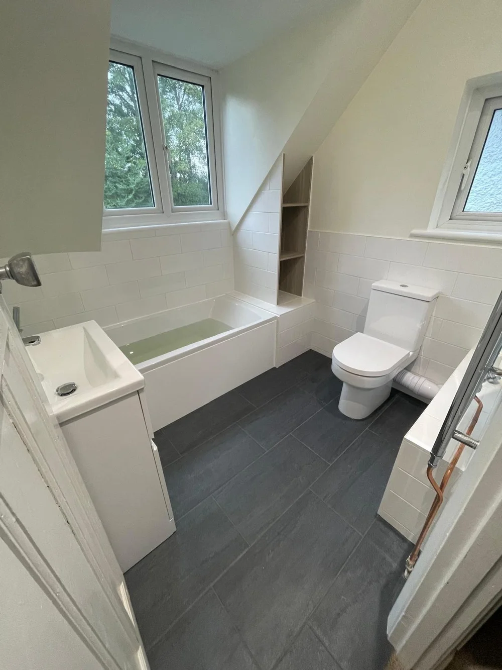 Bright loft family bathroom with metro tiles and slate-tiled floor — bathroom installation Woking