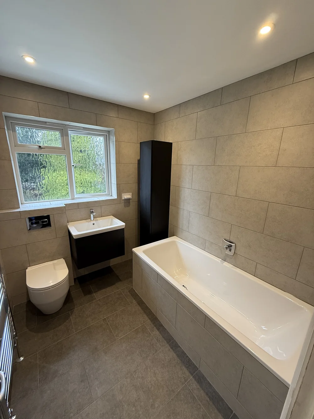 Fitted family bathroom with black vanity, tall storage and built-in bath — bathroom installers Woking