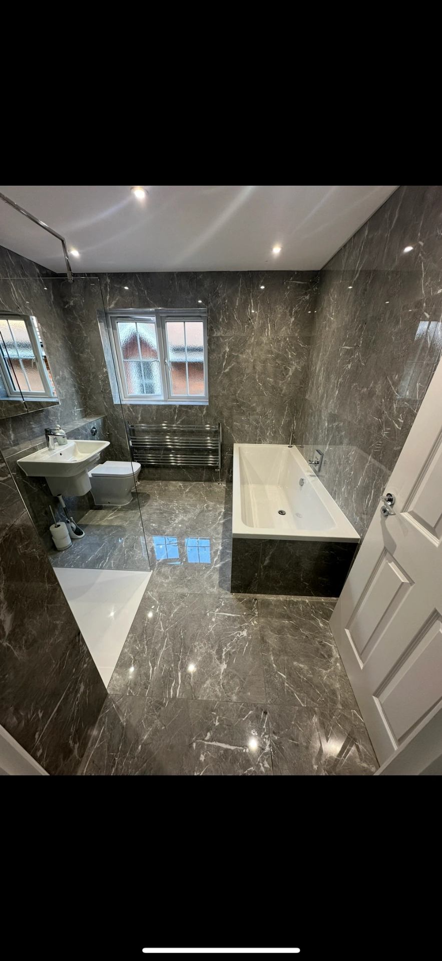 Grey marble family bathroom with double-ended bath and chrome towel rail — Woking