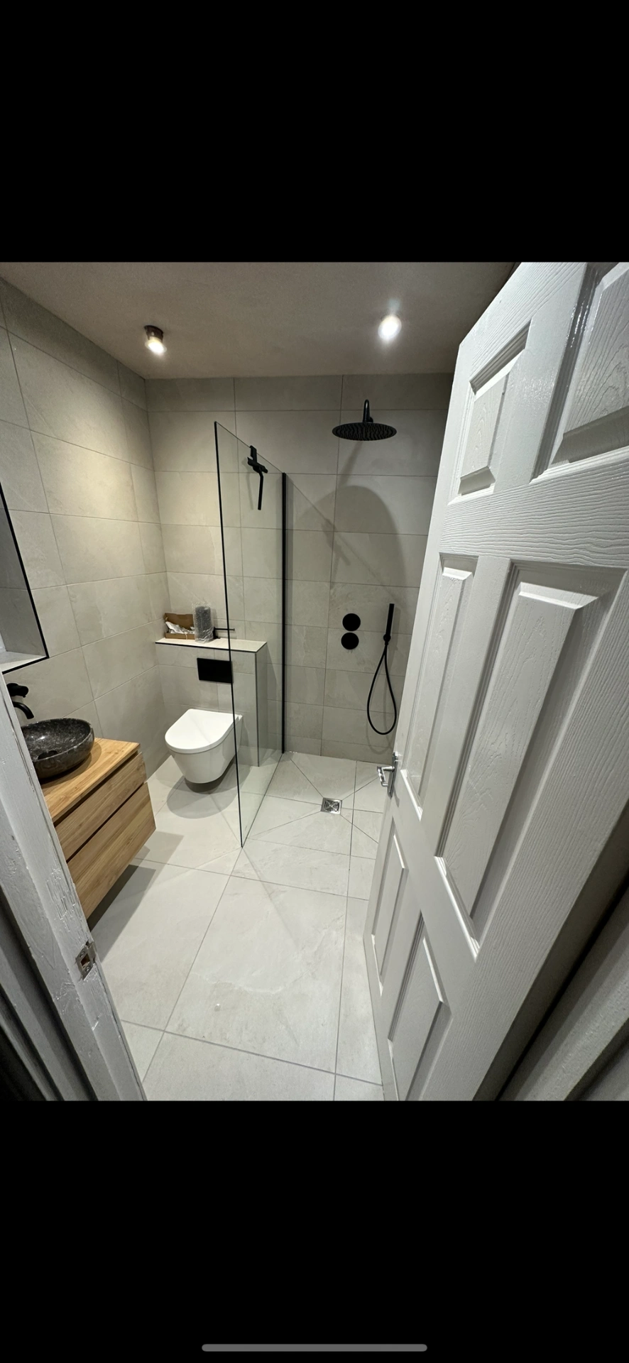 Modern wet room with oak vanity, stone vessel and matte black shower fittings — bathroom installation Woking