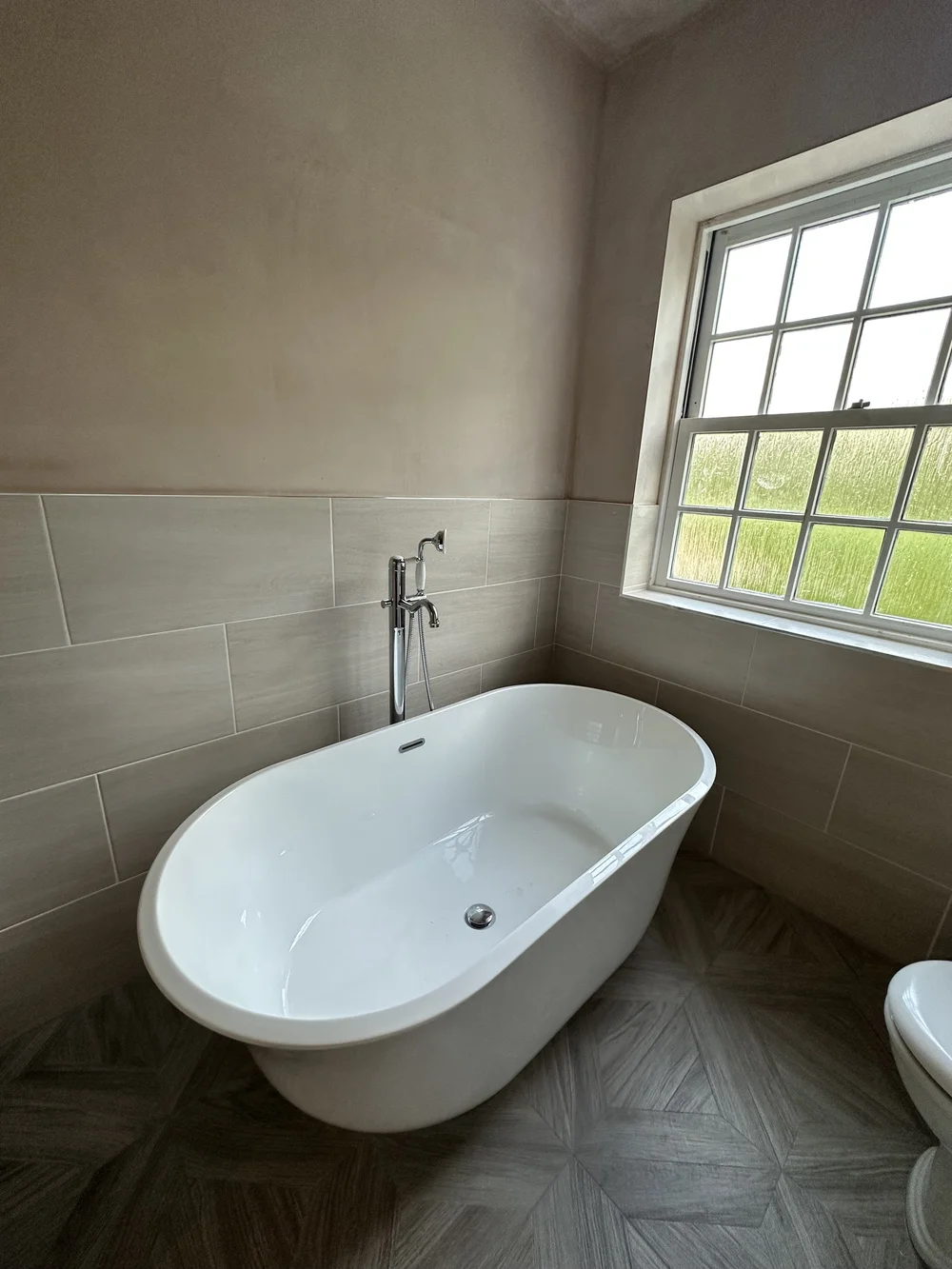 Traditional freestanding double-ended bath with chrome floor-mounted mixer and parquet floor — bathroom installation Woking