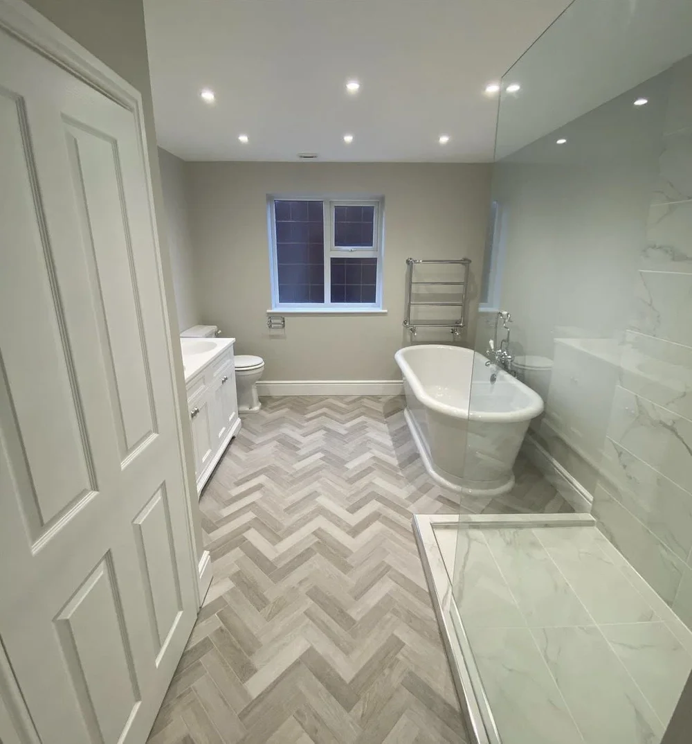 Traditional family bathroom with freestanding roll-top bath, herringbone floor and marble walk-in shower — bathroom installation Woking