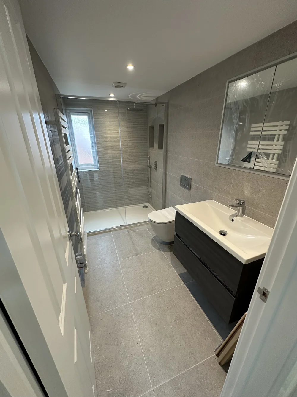 Grey stone-tiled shower room with graphite vanity and glass shower enclosure — bathroom installation Woking