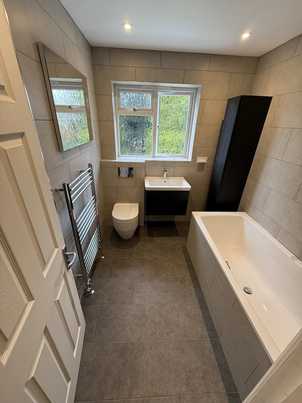 Compact family bathroom with black vanity, wall-hung WC and built-in bath — bathroom installation Woking