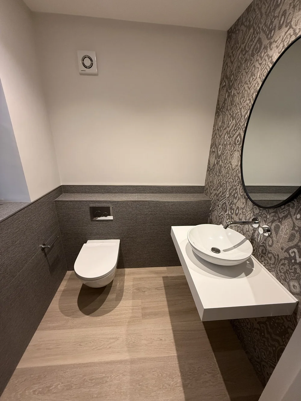 Bespoke cloakroom with patterned wallpaper, oak floor and floating vessel basin — Woking