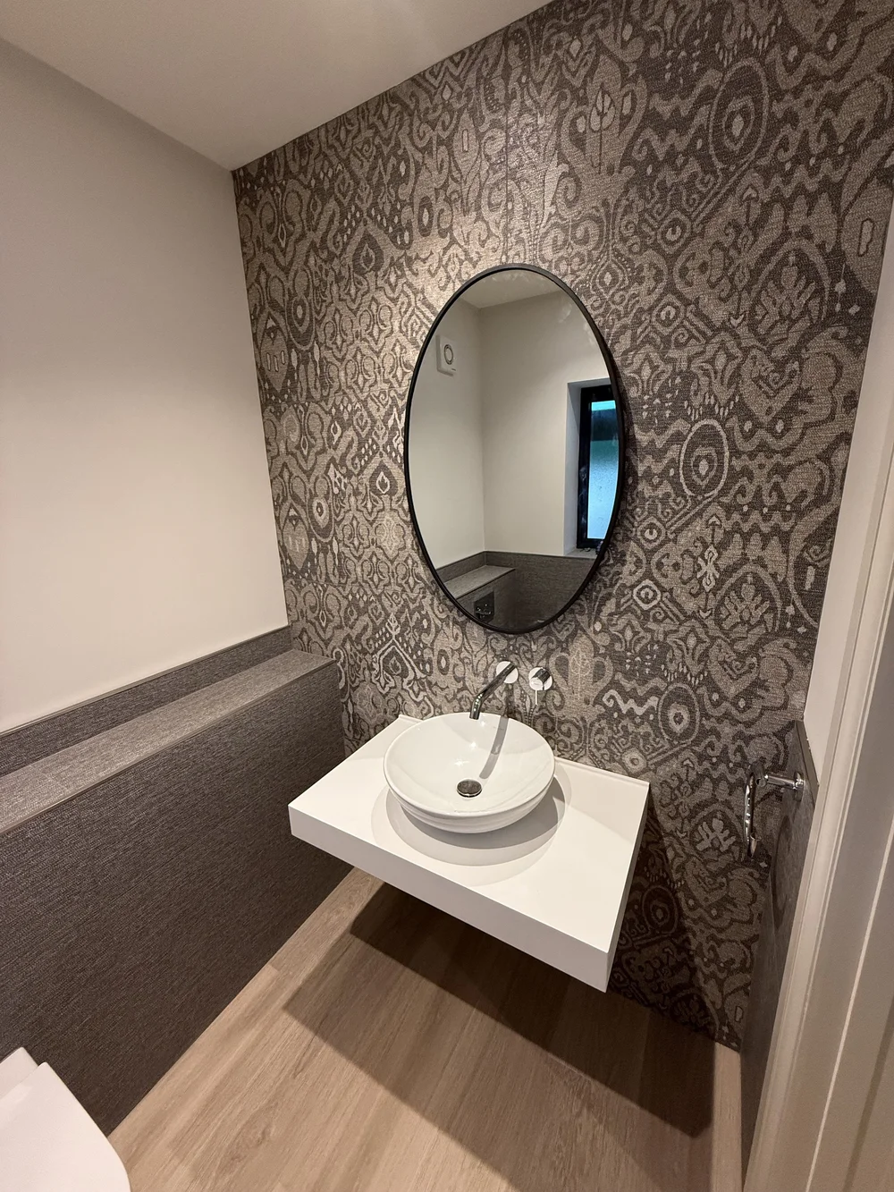 Feature-wall cloakroom with round black mirror and vessel basin — bathroom design Woking