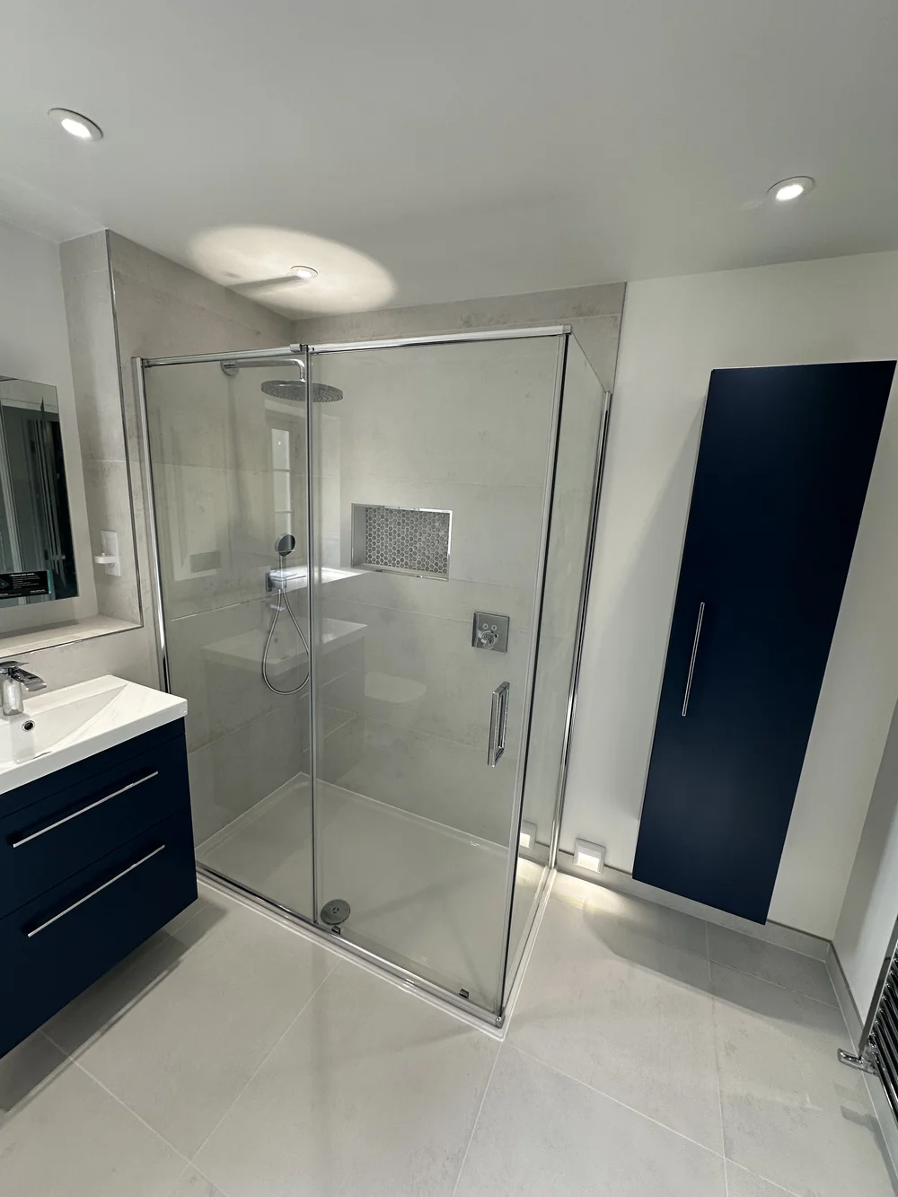 Contemporary shower room with navy wall cabinet, floating vanity and walk-in shower — bathroom installation Woking