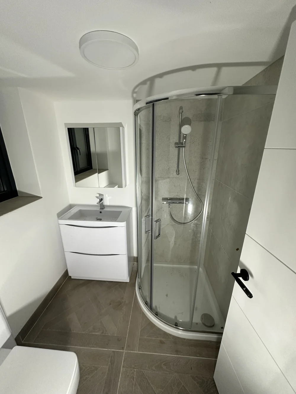 Loft shower room with quadrant enclosure, herringbone tile floor and floor-standing vanity — bathroom installation Woking