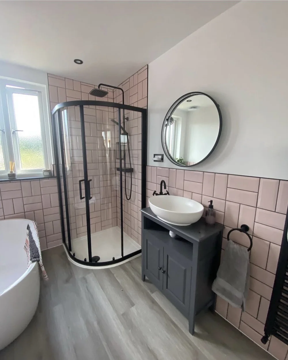 Pink metro-tiled bathroom with black-framed quadrant shower, freestanding bath and vessel basin — bathroom renovation Woking