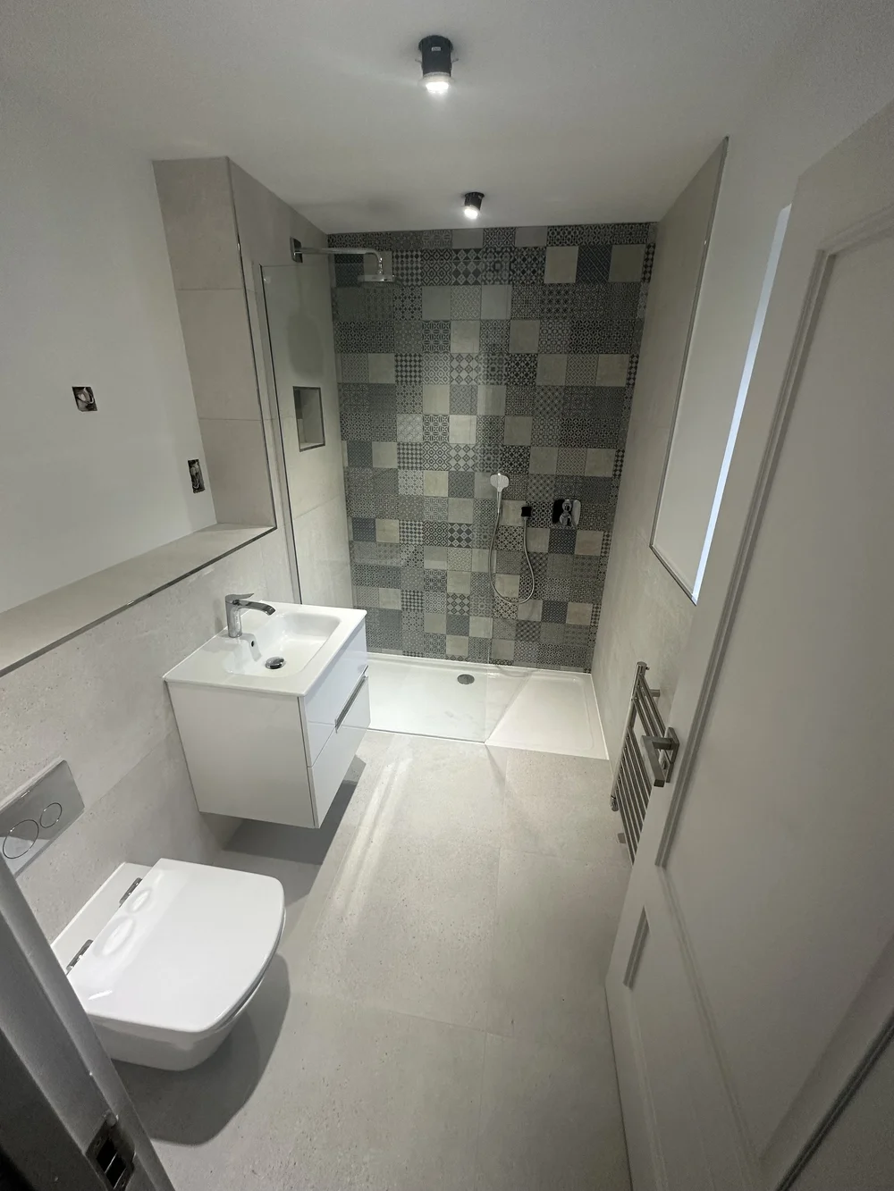 Compact shower room with patchwork feature wall and floating white vanity — bathroom installation Woking