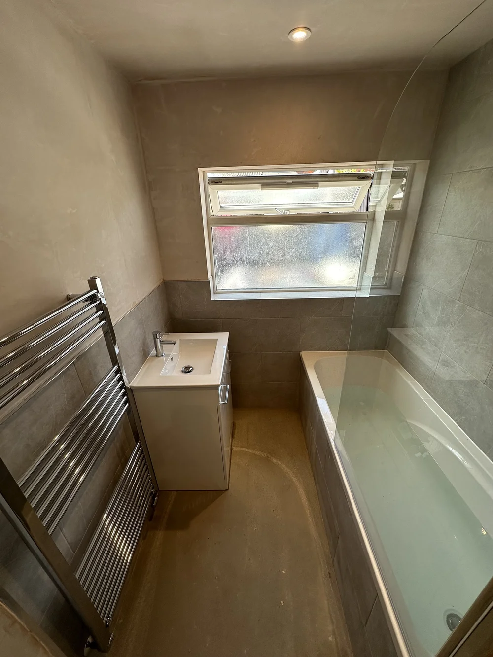 Compact family bathroom mid-renovation with fresh plaster, stone tiling and new bath — bathroom renovation Woking