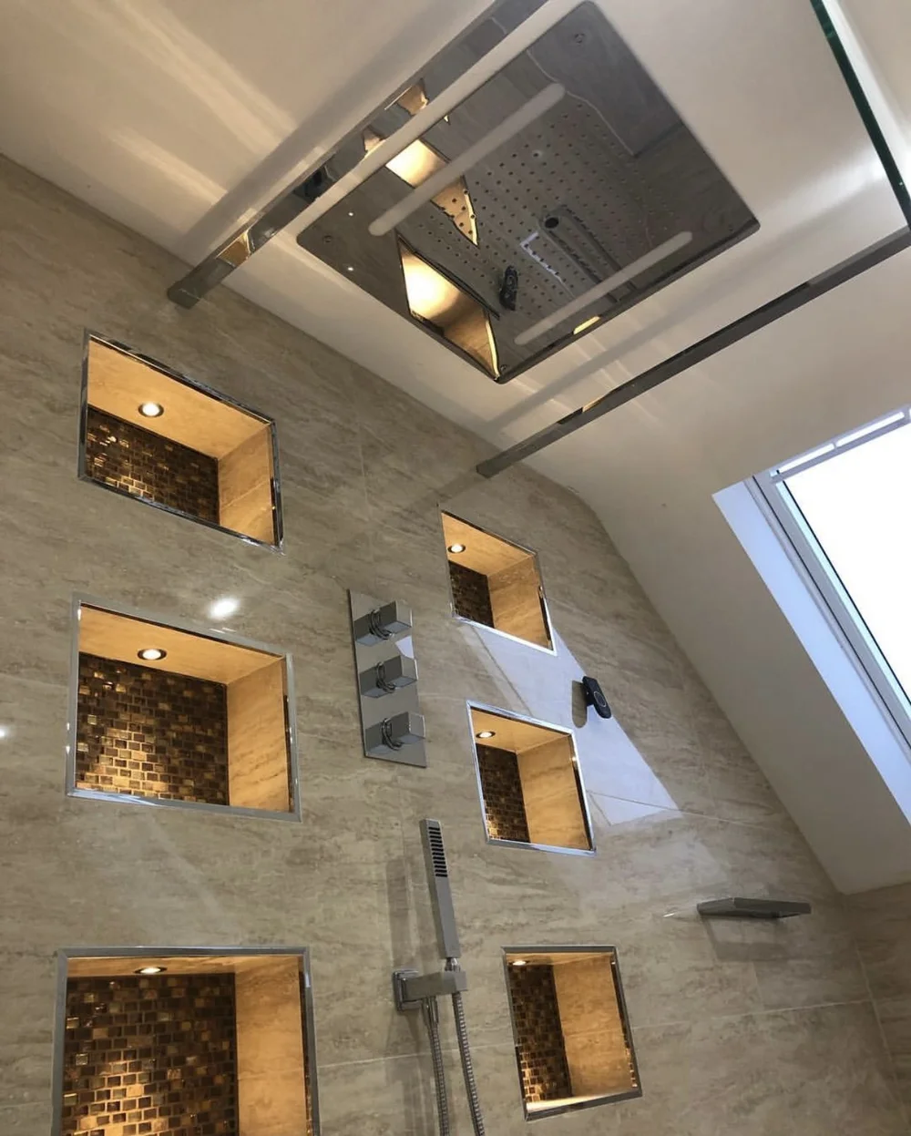 Ceiling rainfall panel with LED strip lighting over travertine walk-in shower — luxury bathroom installation Woking