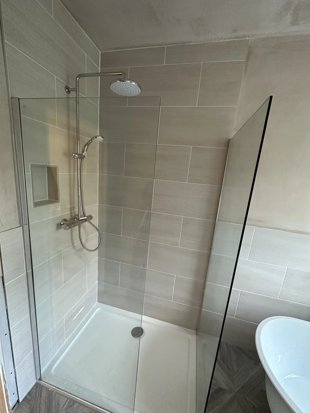 Walk-in shower with cream metro tiles, brushed nickel rainfall column and glass screen — bathroom installation Woking